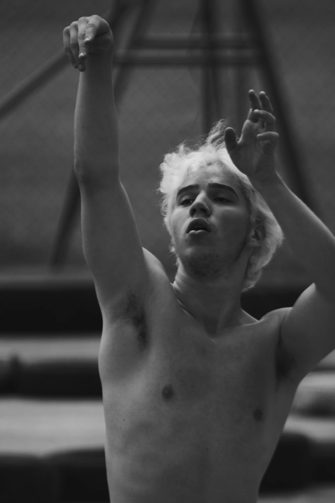 A portrait of a shirtless blonde-haired young man in a pose after a basketball shot