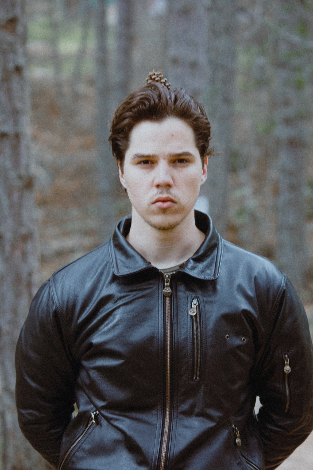 A man in a black leather jacket with a pinecone on his head