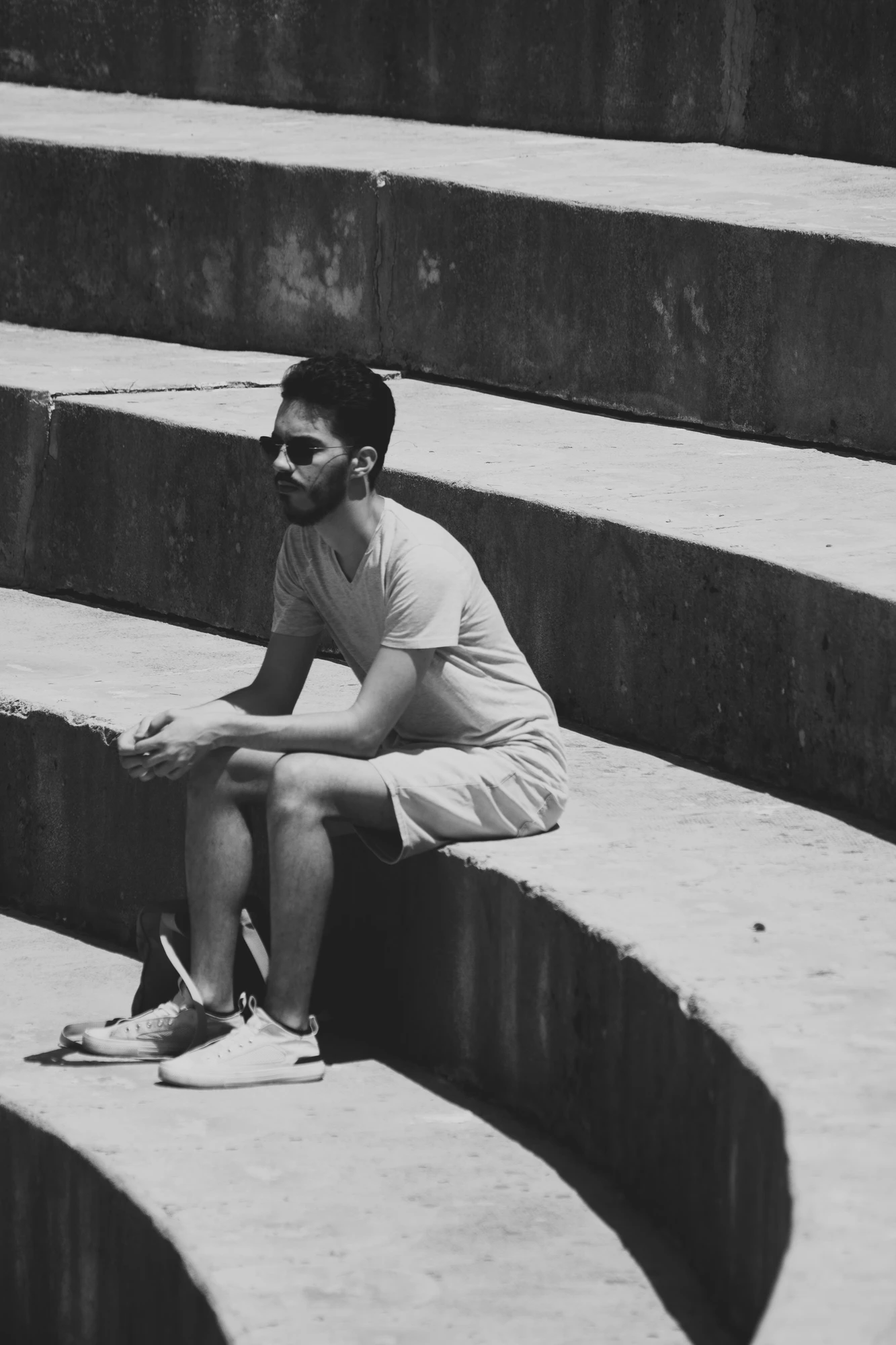 A person with sunglasses sitting on amphitheatre stairs