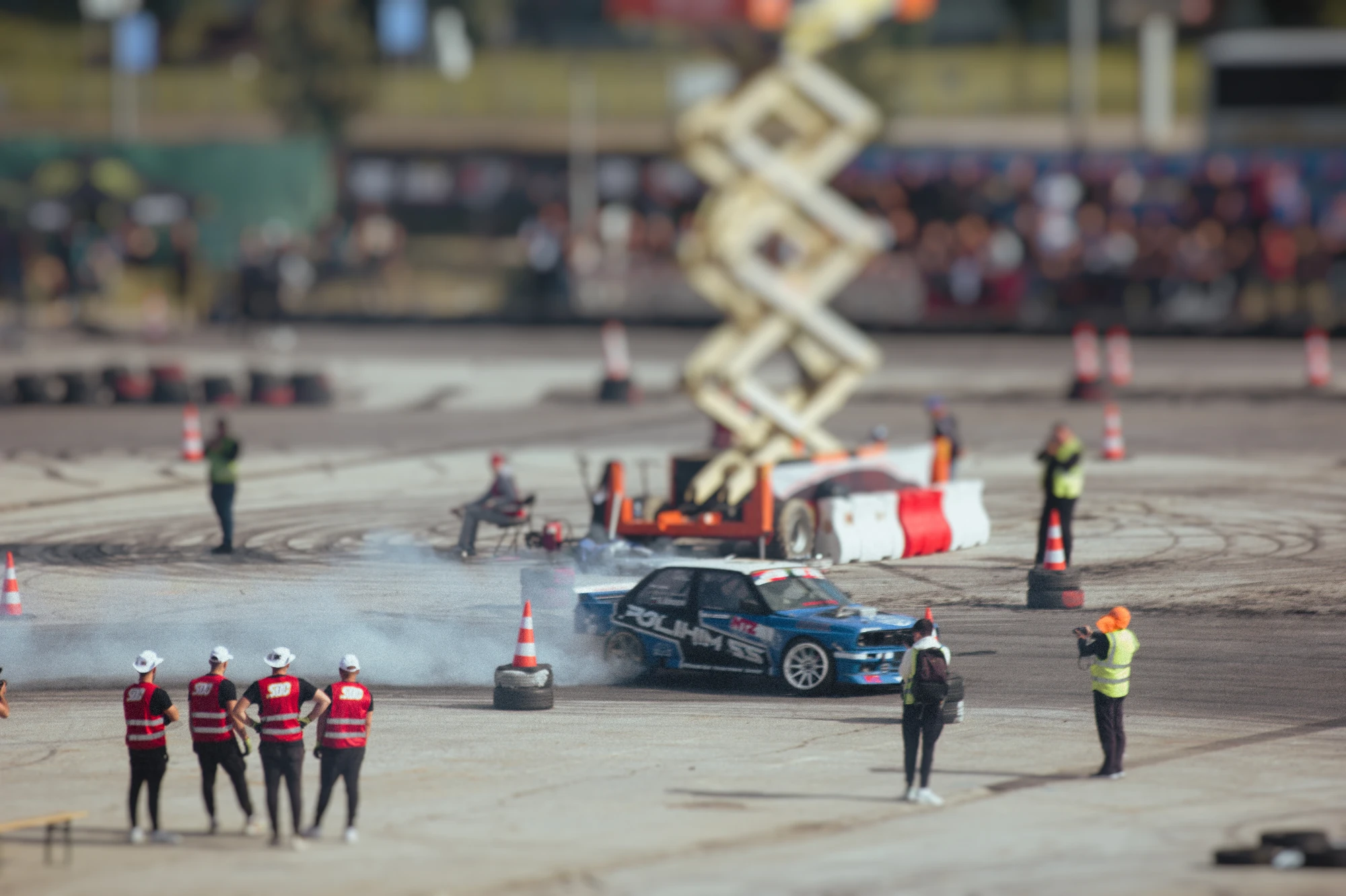 Many people standing around a car on the track