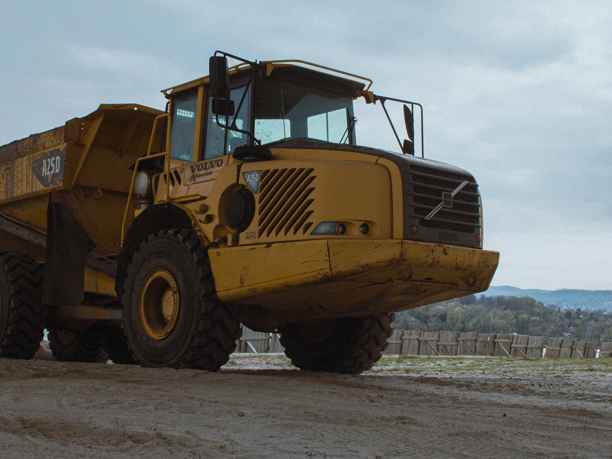 A yellow dump truck parked on dirt in a field