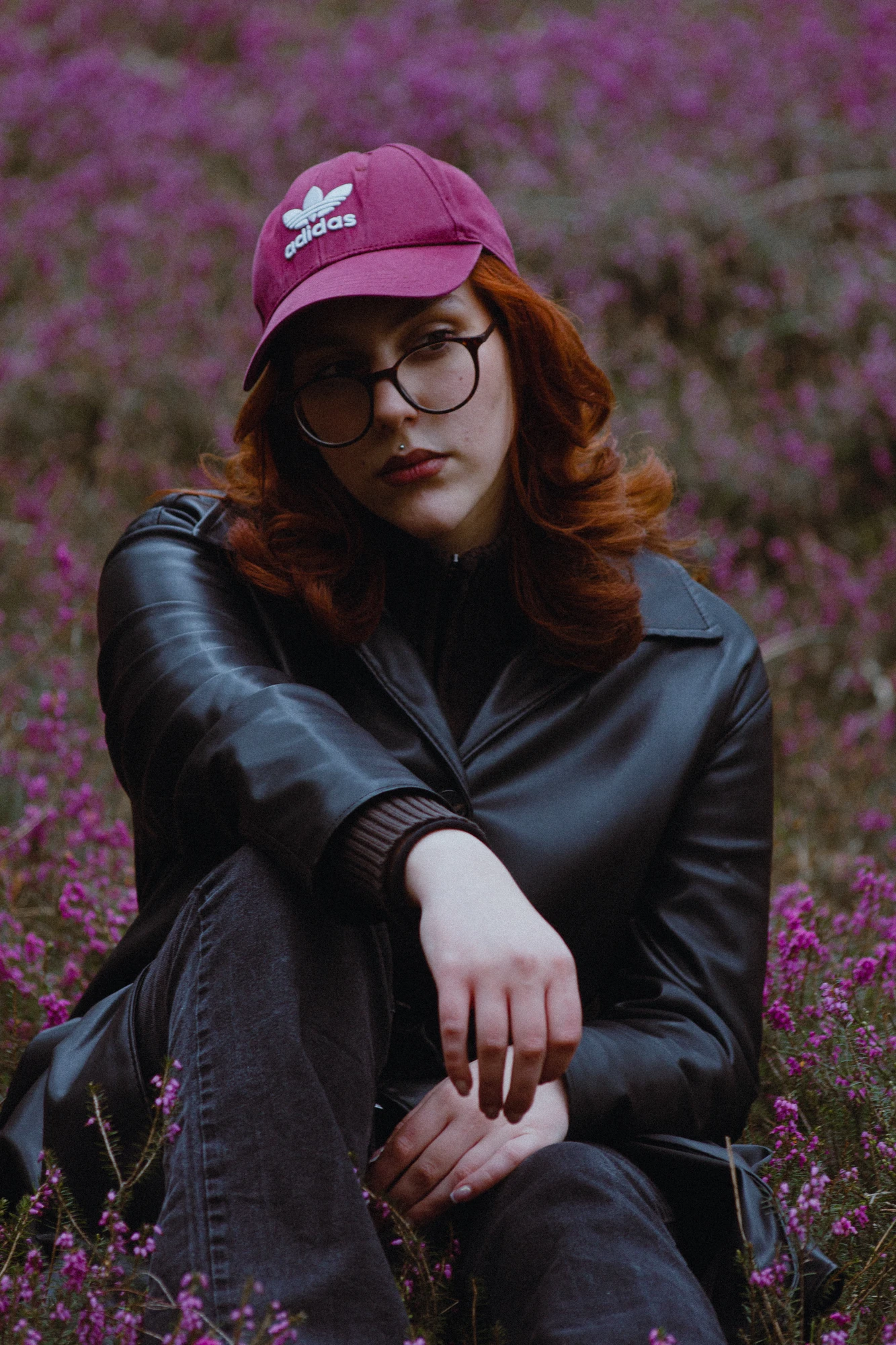 A woman with a purple cap sitting in a field of purple flowers
