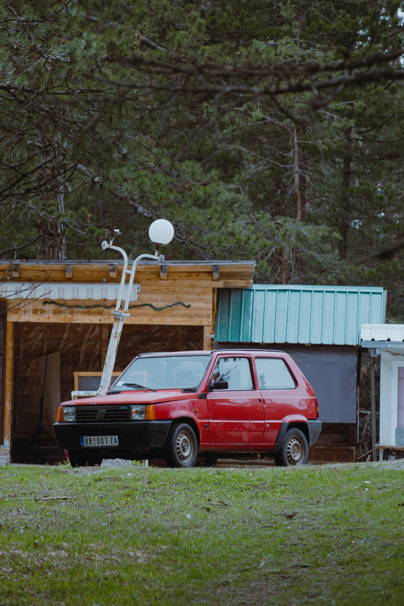 A small red car parked somewhere in the forest