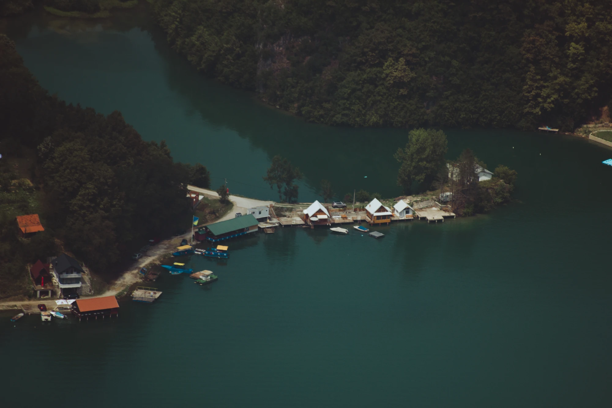 A few raft houses on a lake surrounded by forest