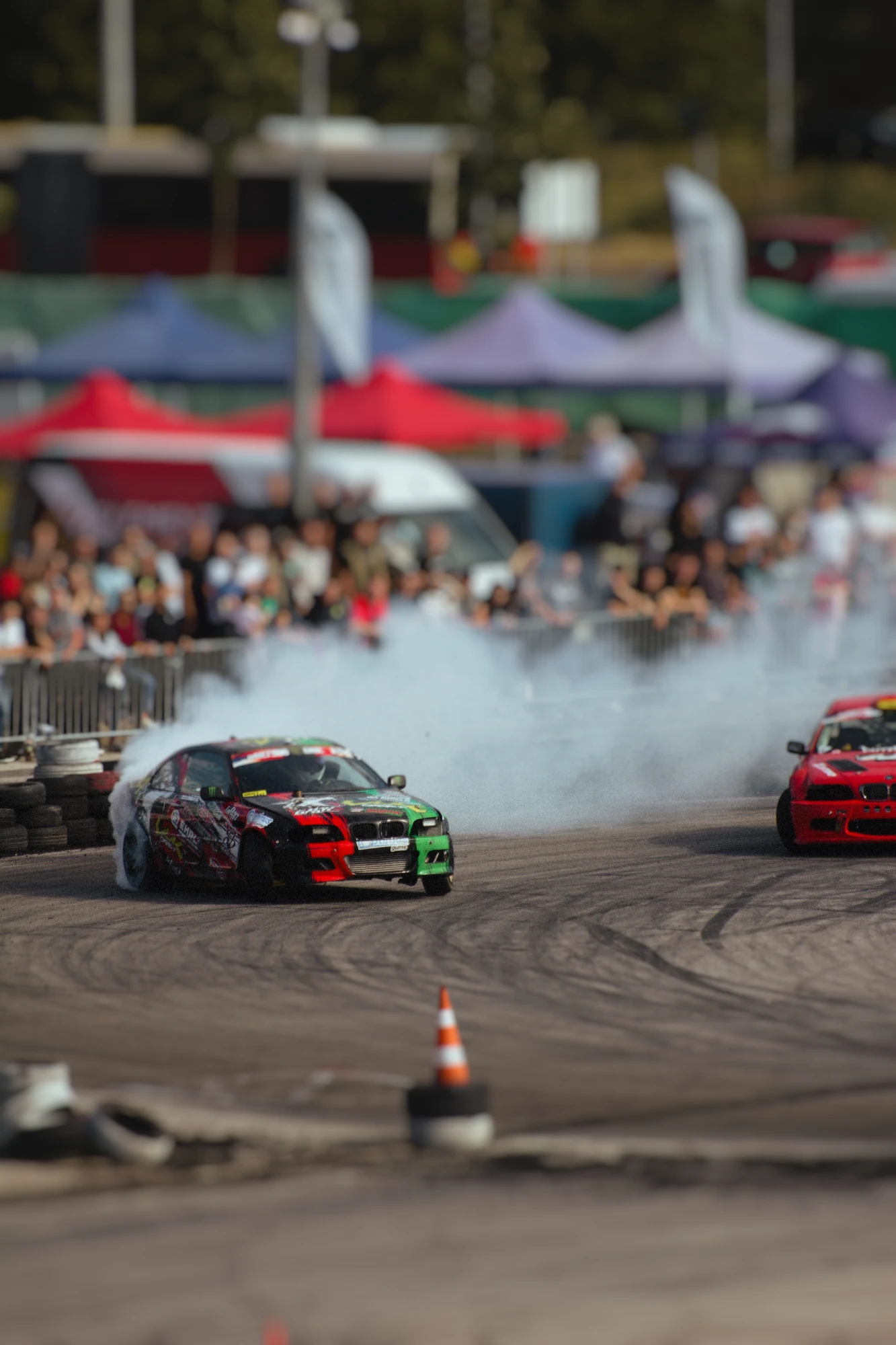Two cars racing around a track with smoking tyres