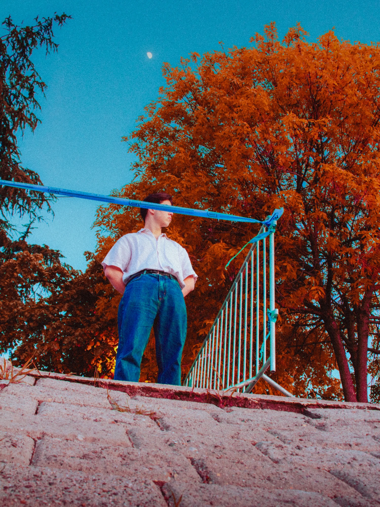 A man standing behind a safety tape with half moon in the sky
