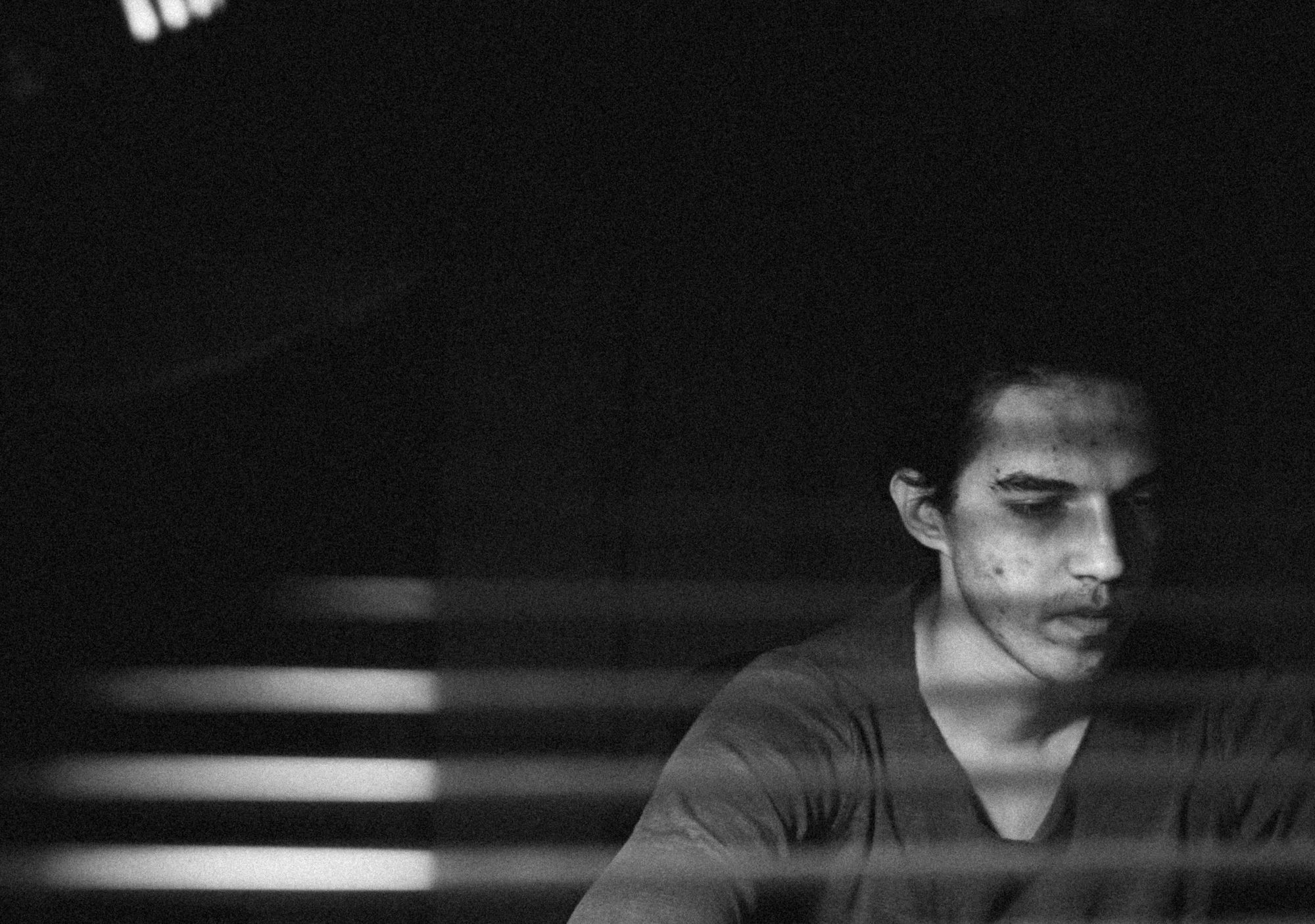 A portrait of a young man behind a window blinds