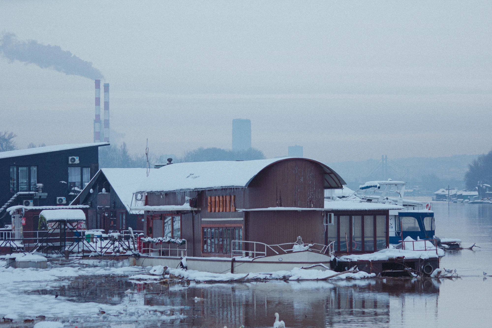 Snowy scene of a boathouse and a boat in the water