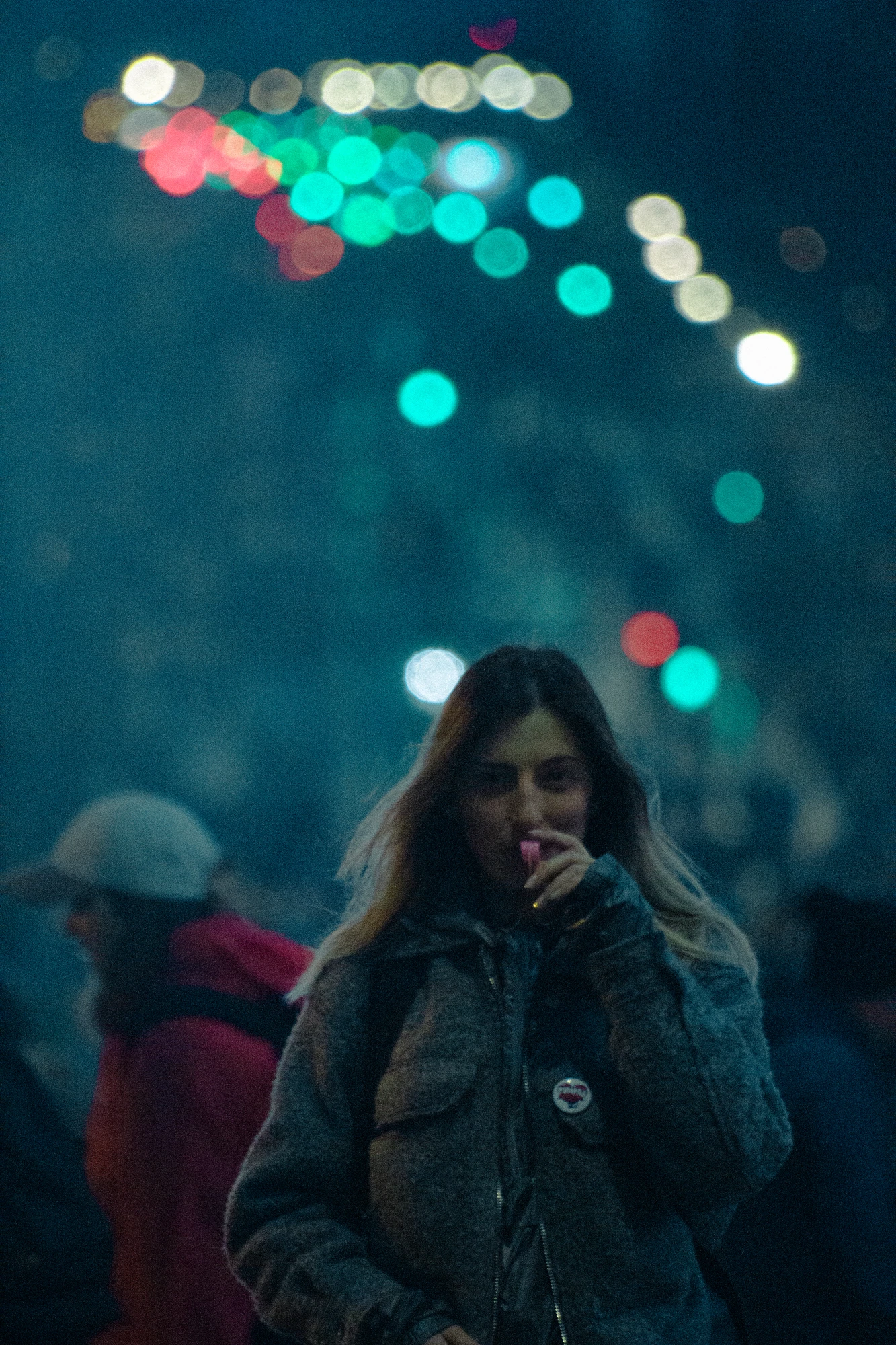 A woman blowing a whistle at night in a crowder area