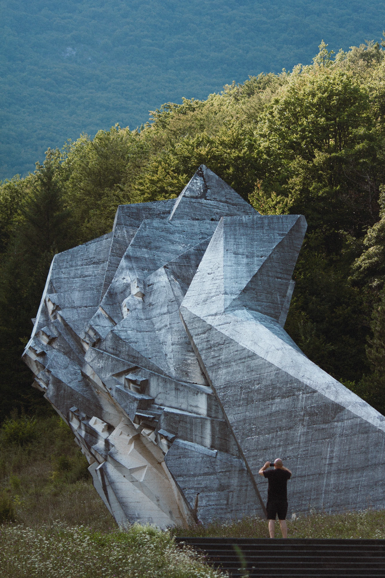 A man photographing a large concrete memorial