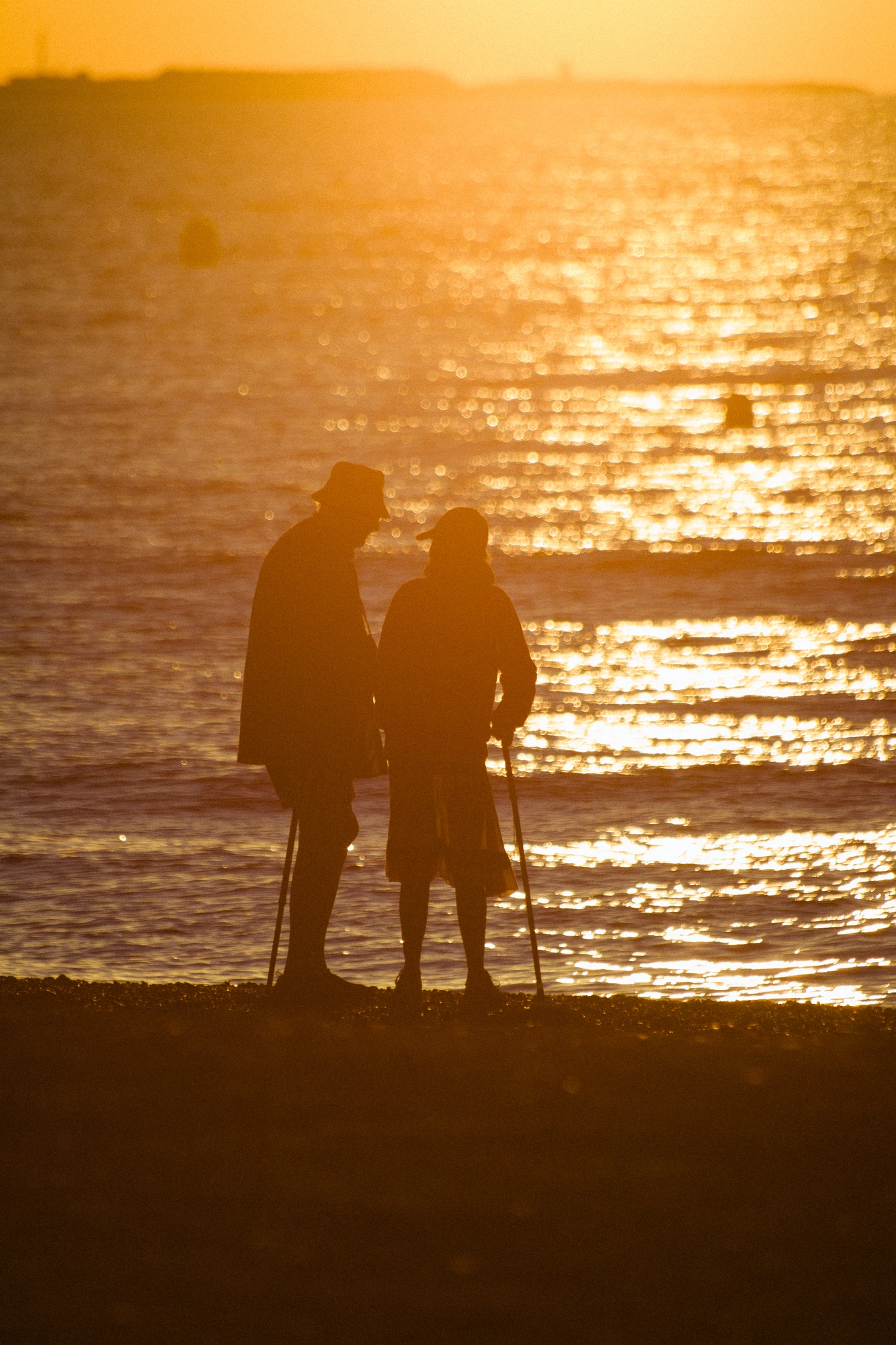 An old couple walking down the beach at sunrise