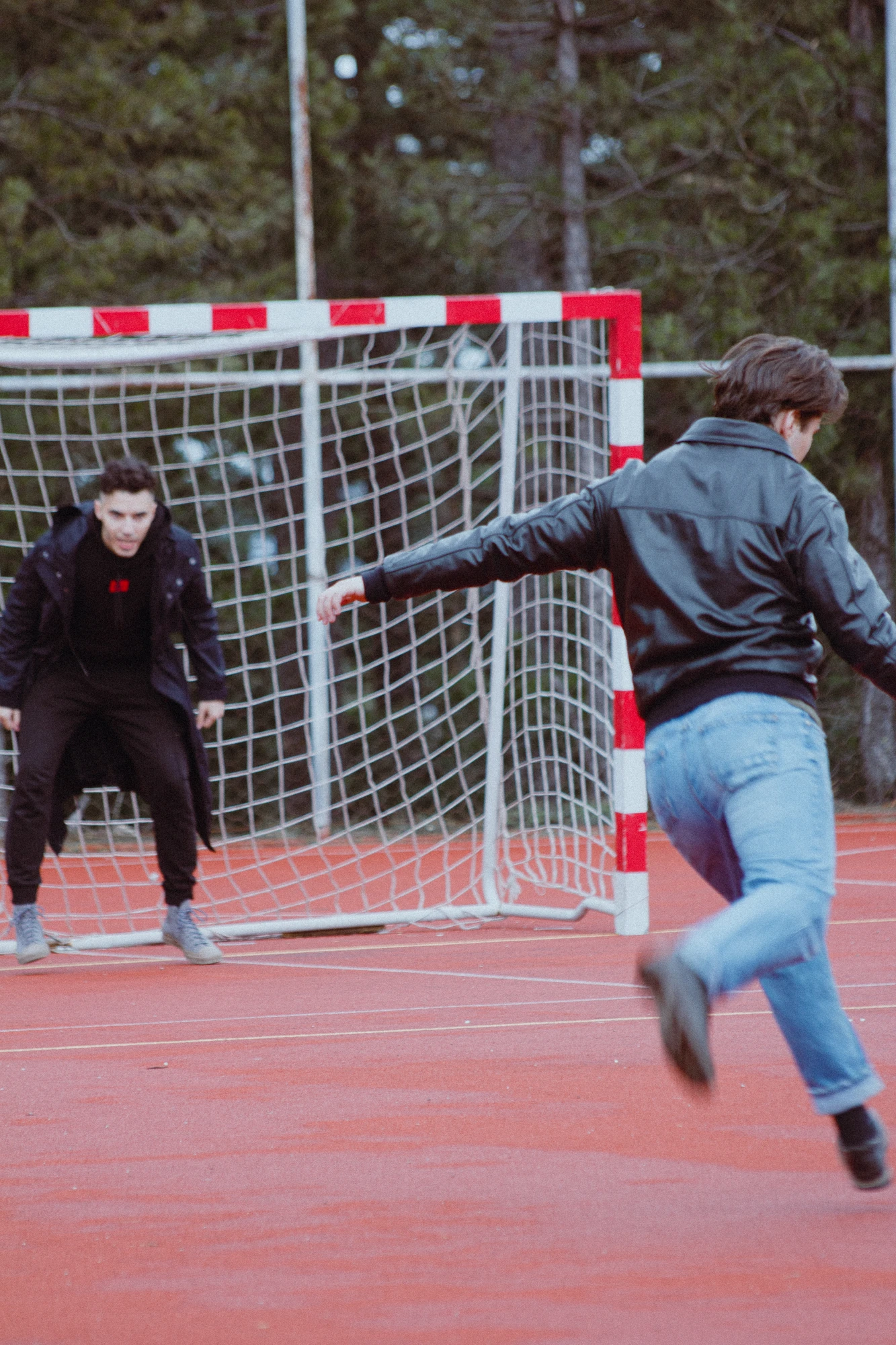 Two men playing soccer on a red court