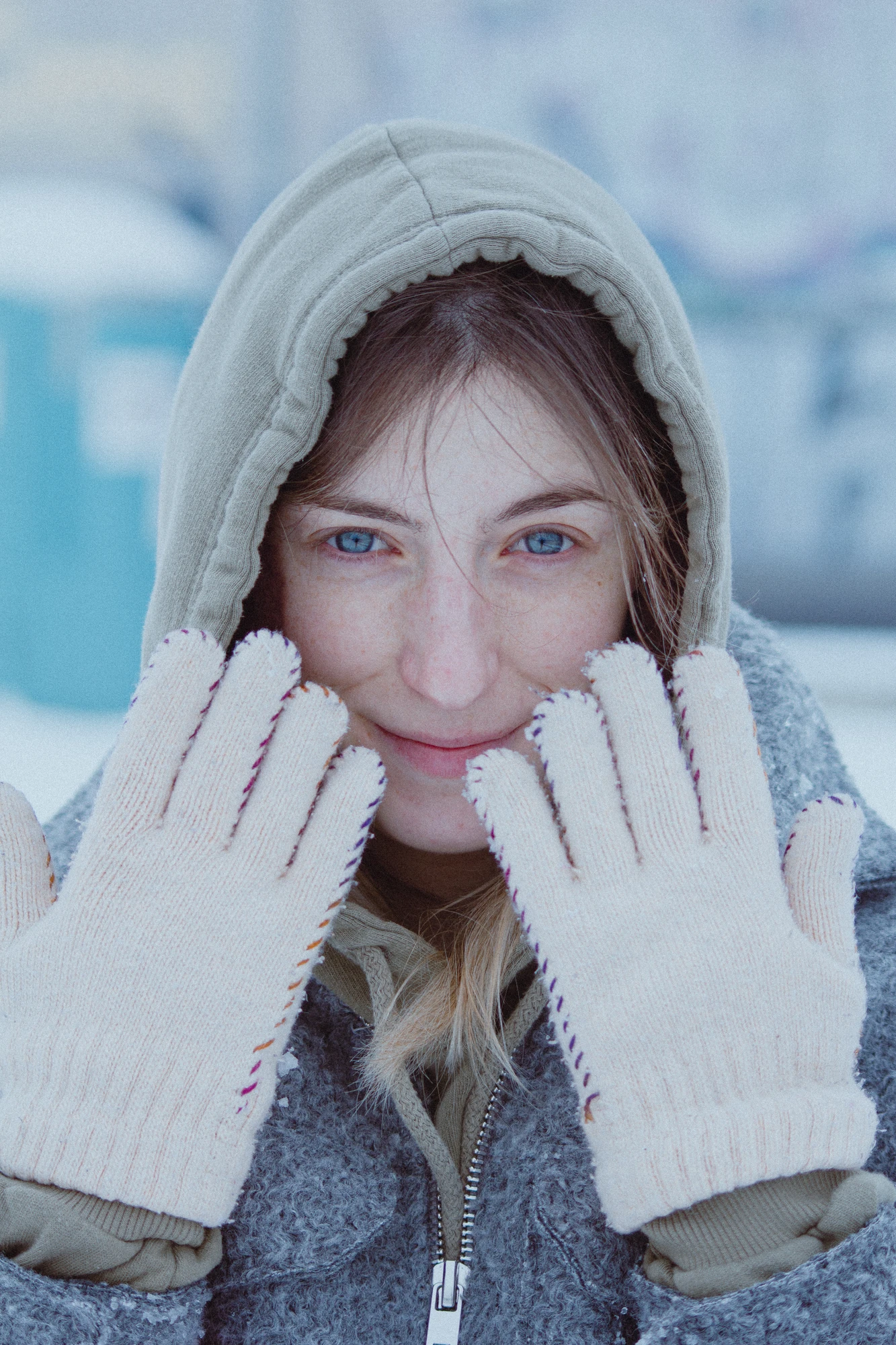 A woman with blue eyes in a gray jacket and white gloves