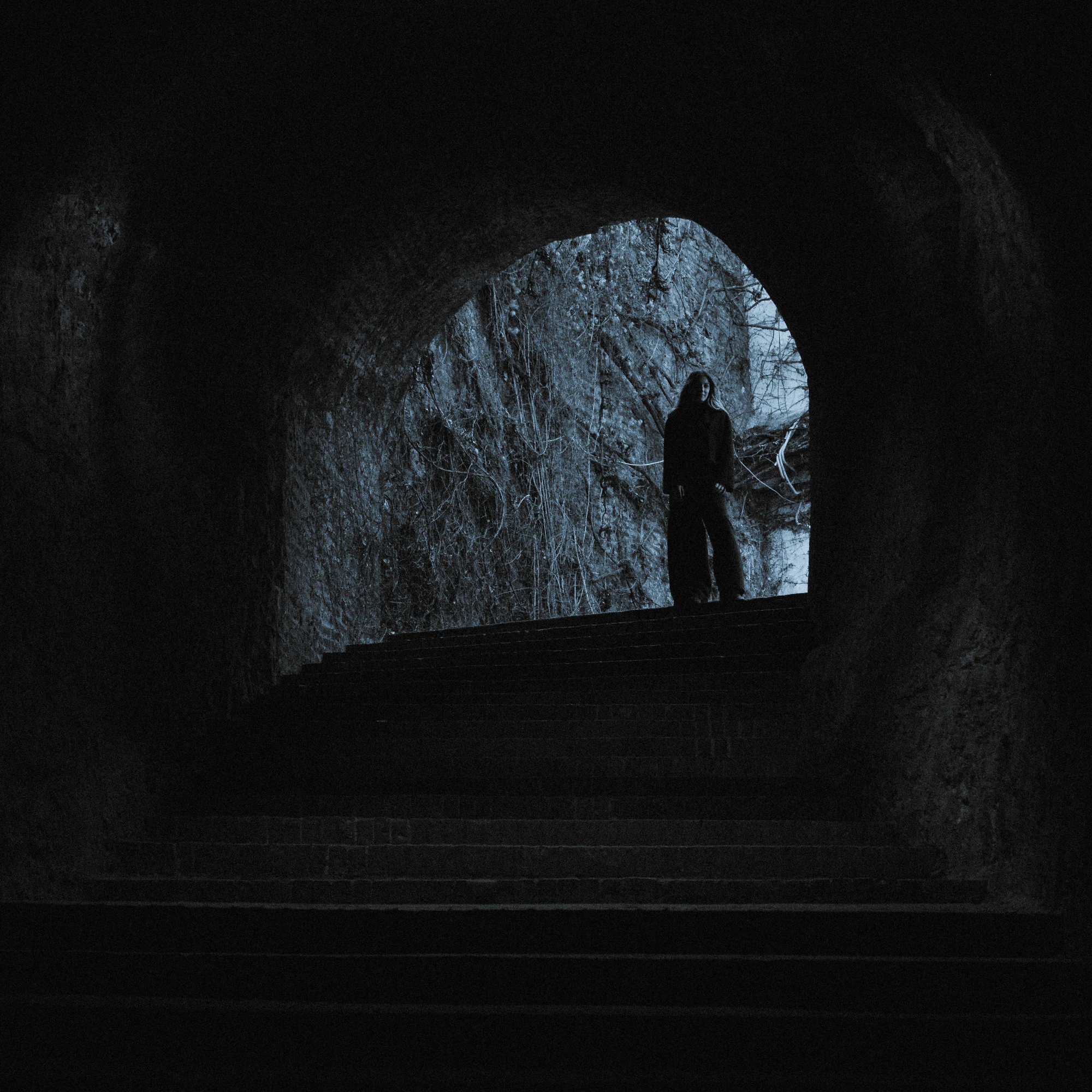 A woman standing in a tunnel with stairs