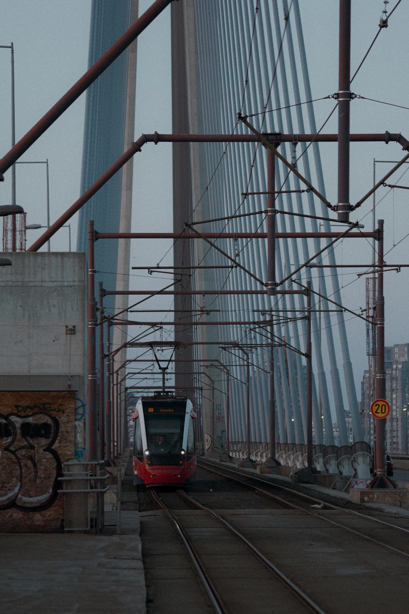 A tram going over a bridge with graffiti on it