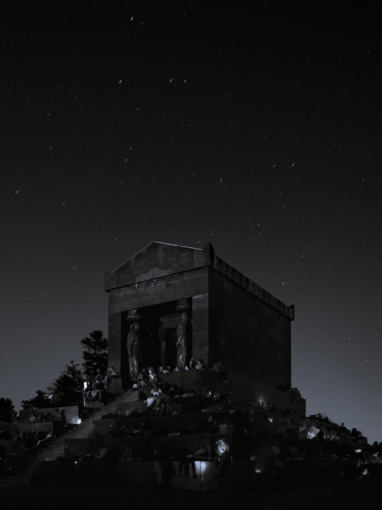 Crowd gathered at a monument at night under a starry sky