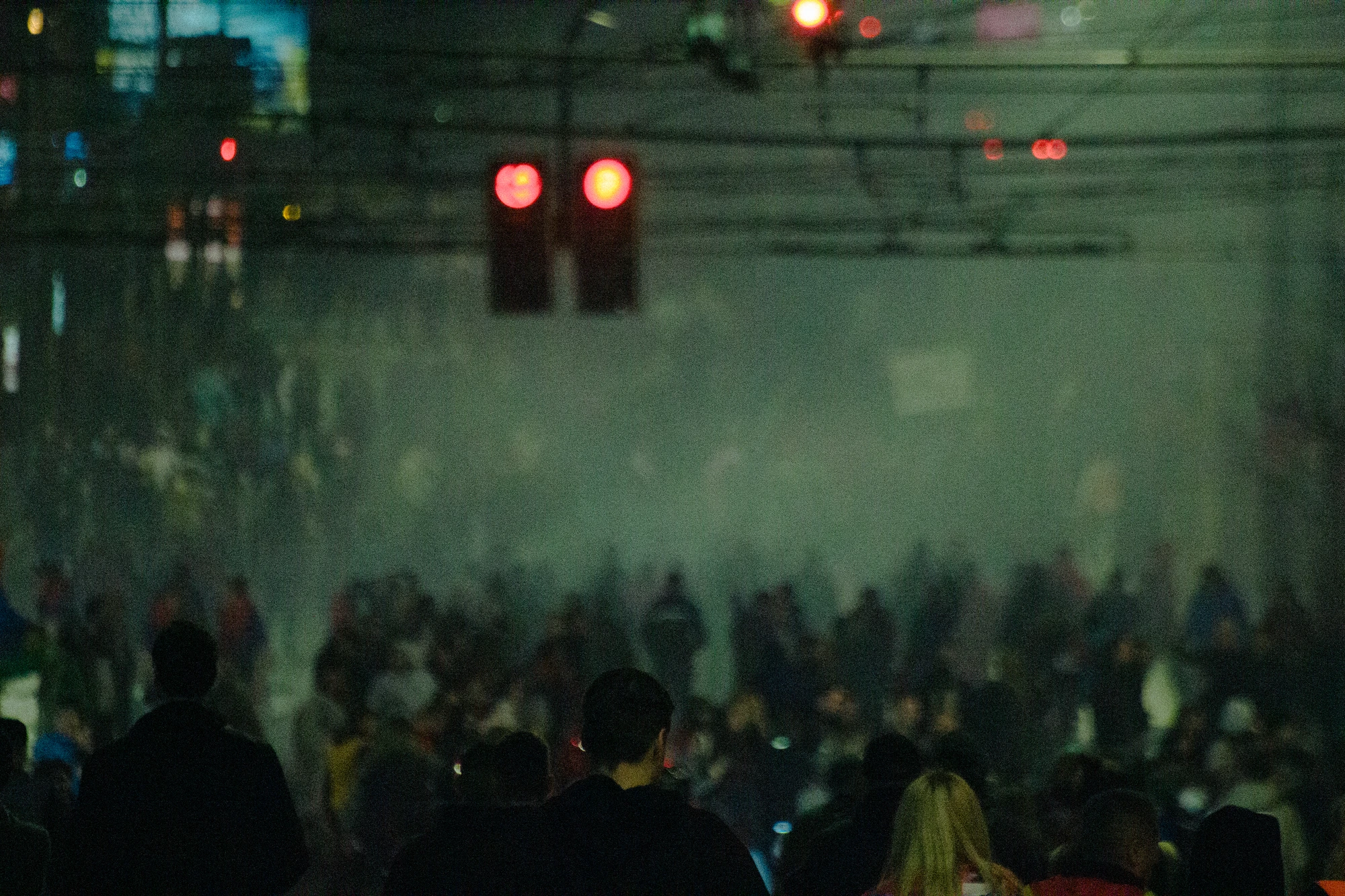 Many people standing in a crowded area at night