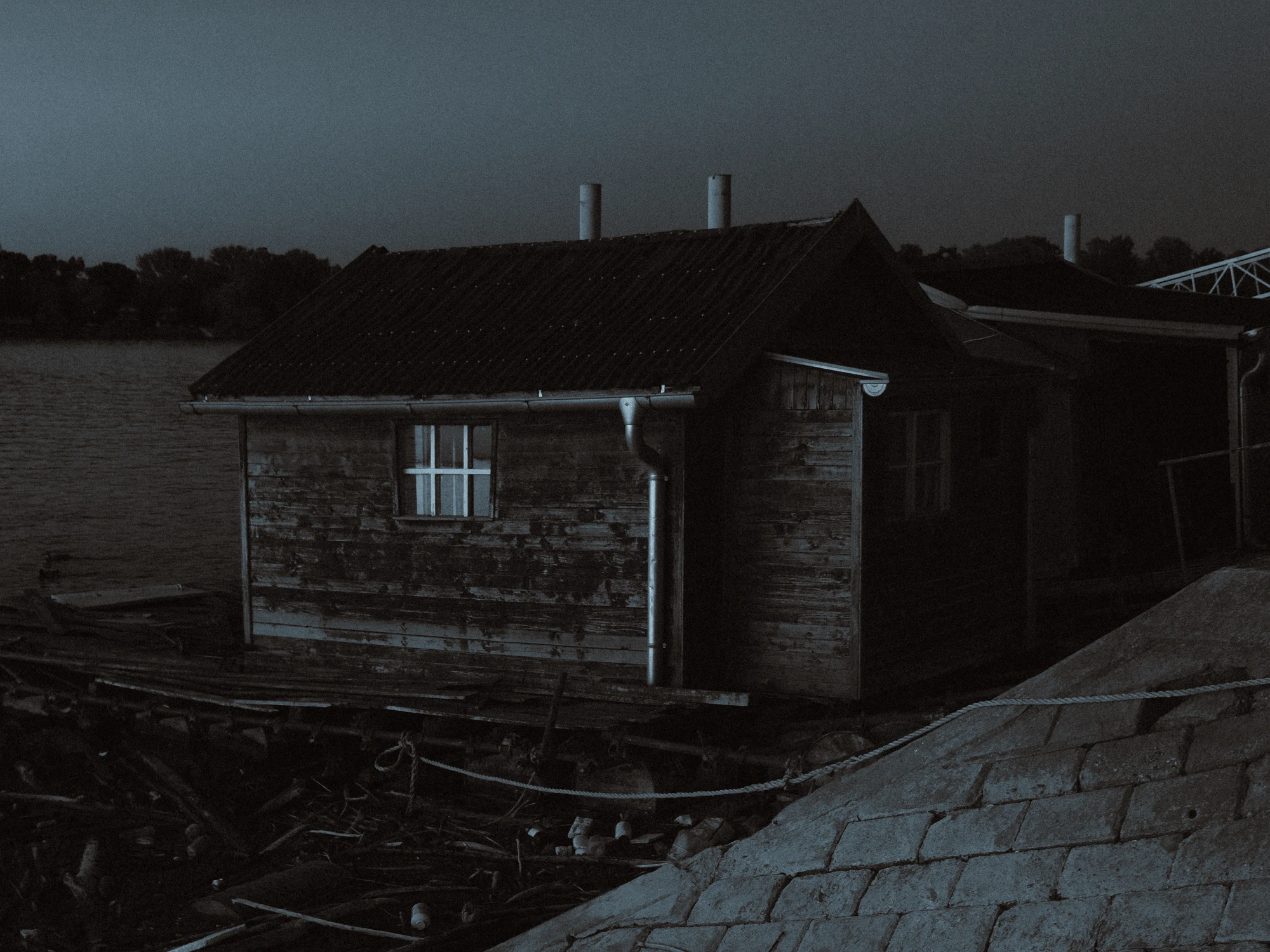 A desolate raft house on a river bank at dusk