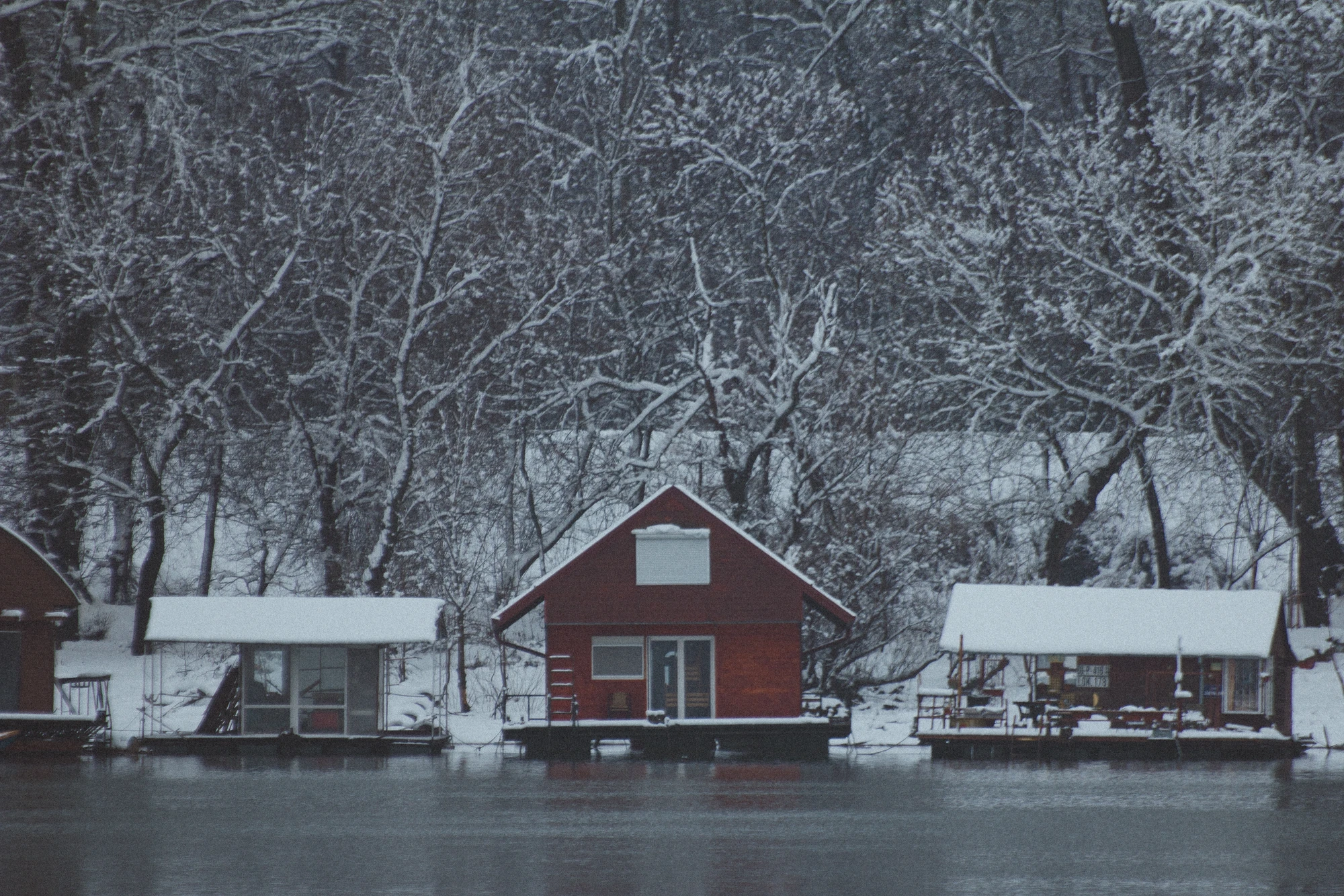 Red raft-house on a river bank in the snow