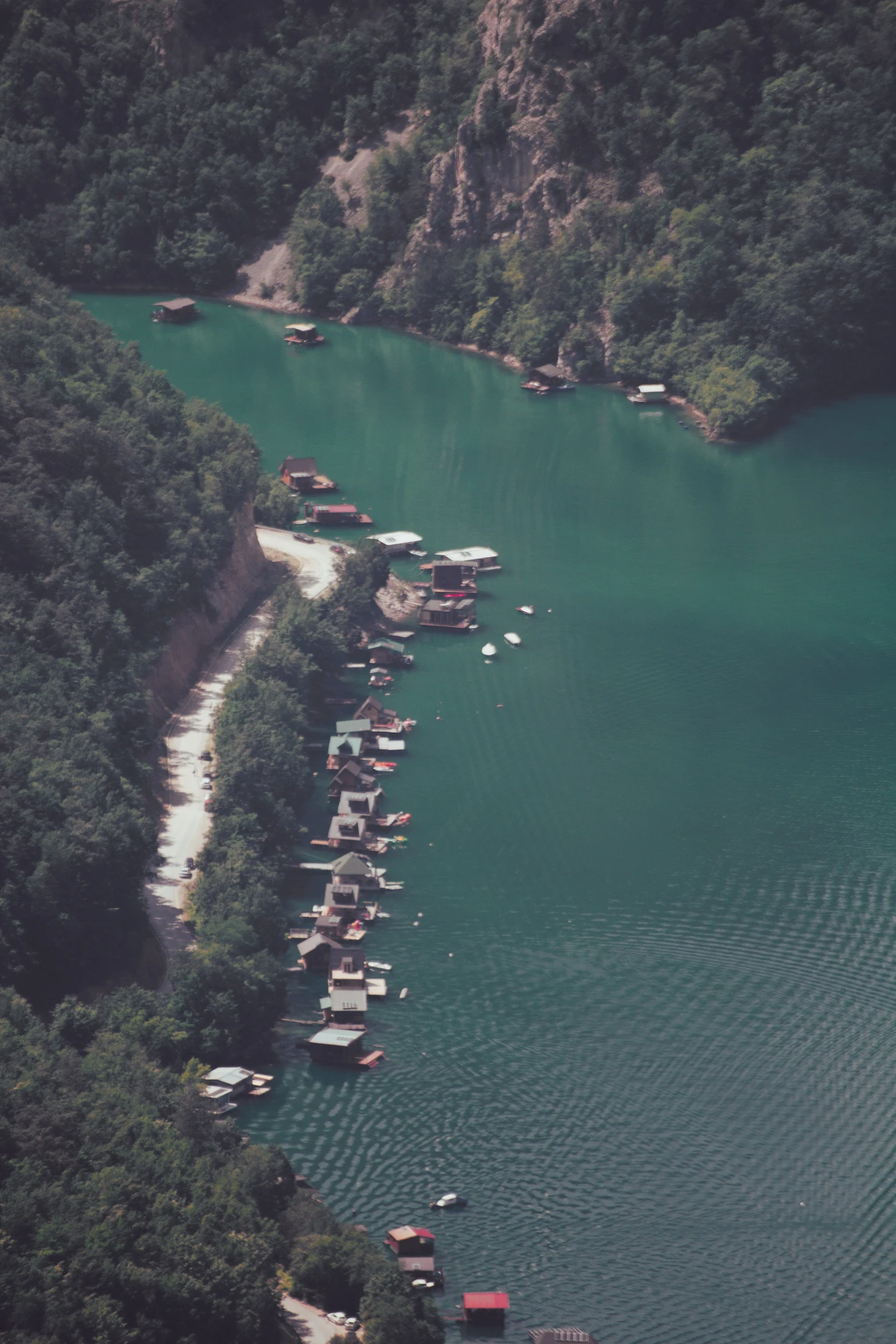 A lake with a bunch of raft-houses next to the road