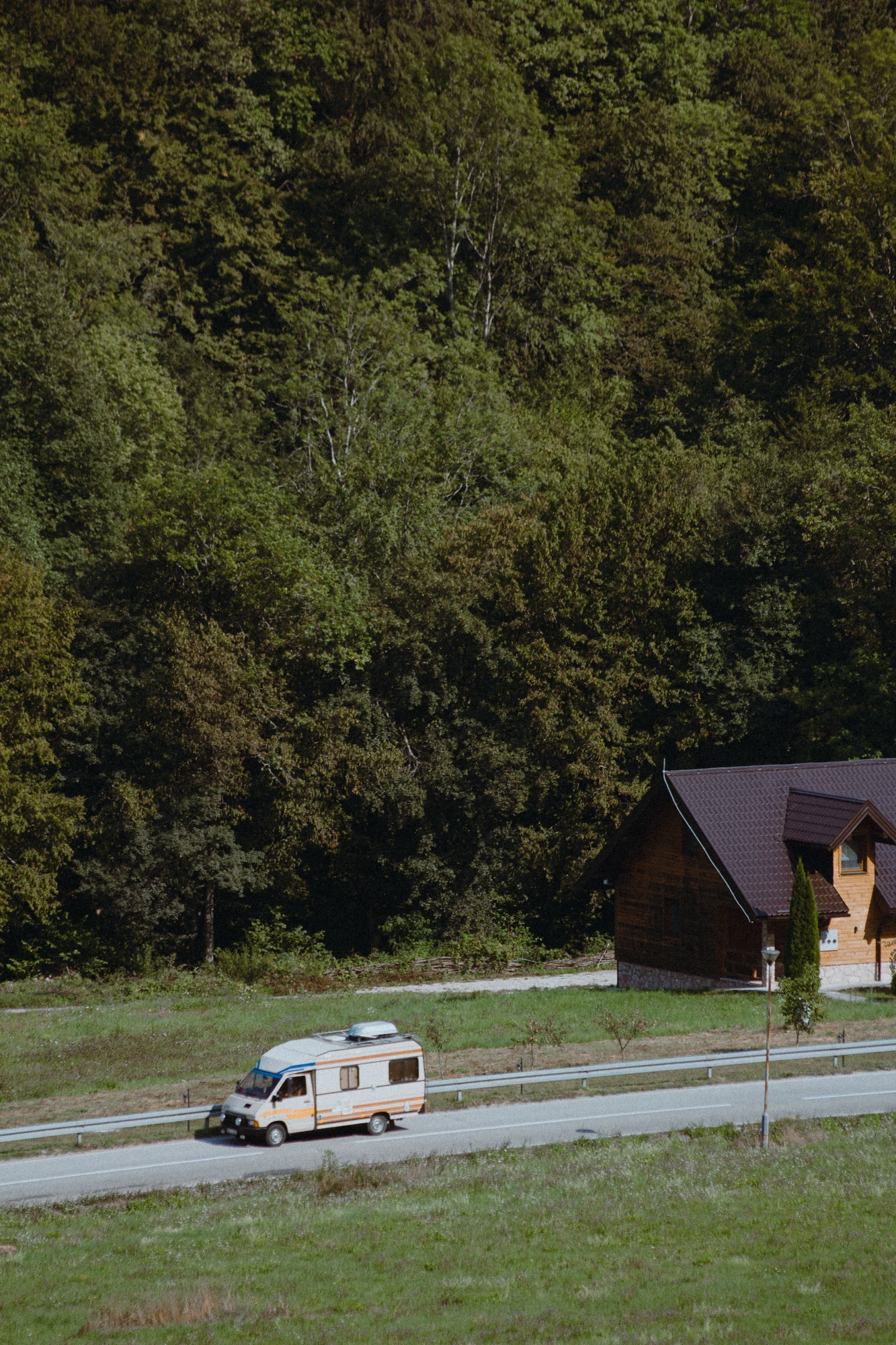 A van driving down the road near a cabin
