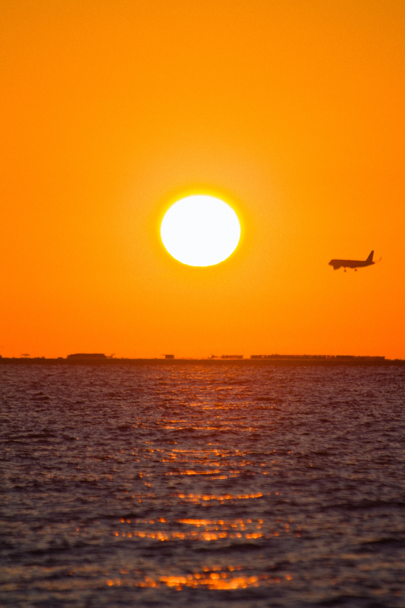 Airplane flying over the sea at sunrise