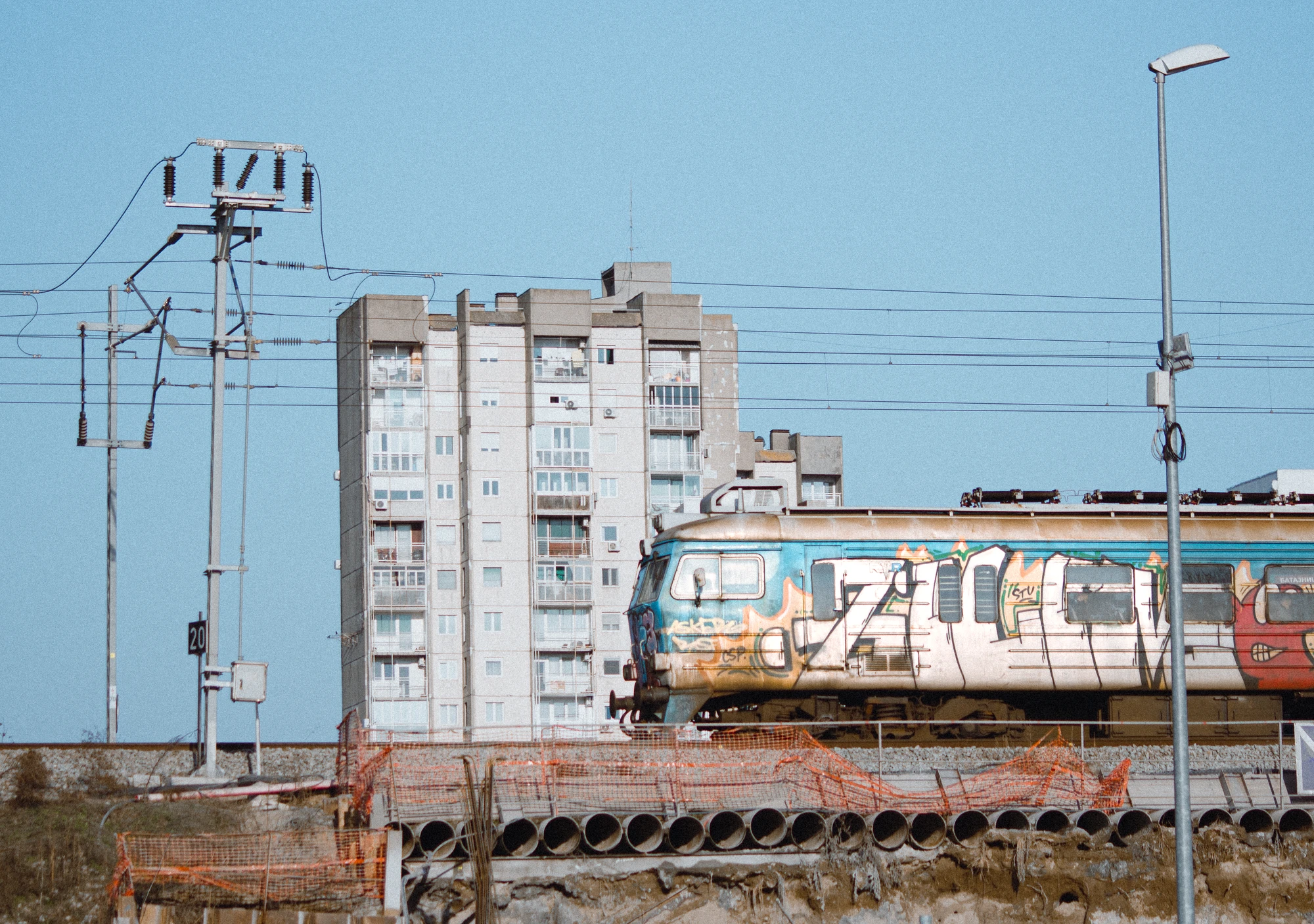 Graffiti-covered train passing an apartment building near a construction site