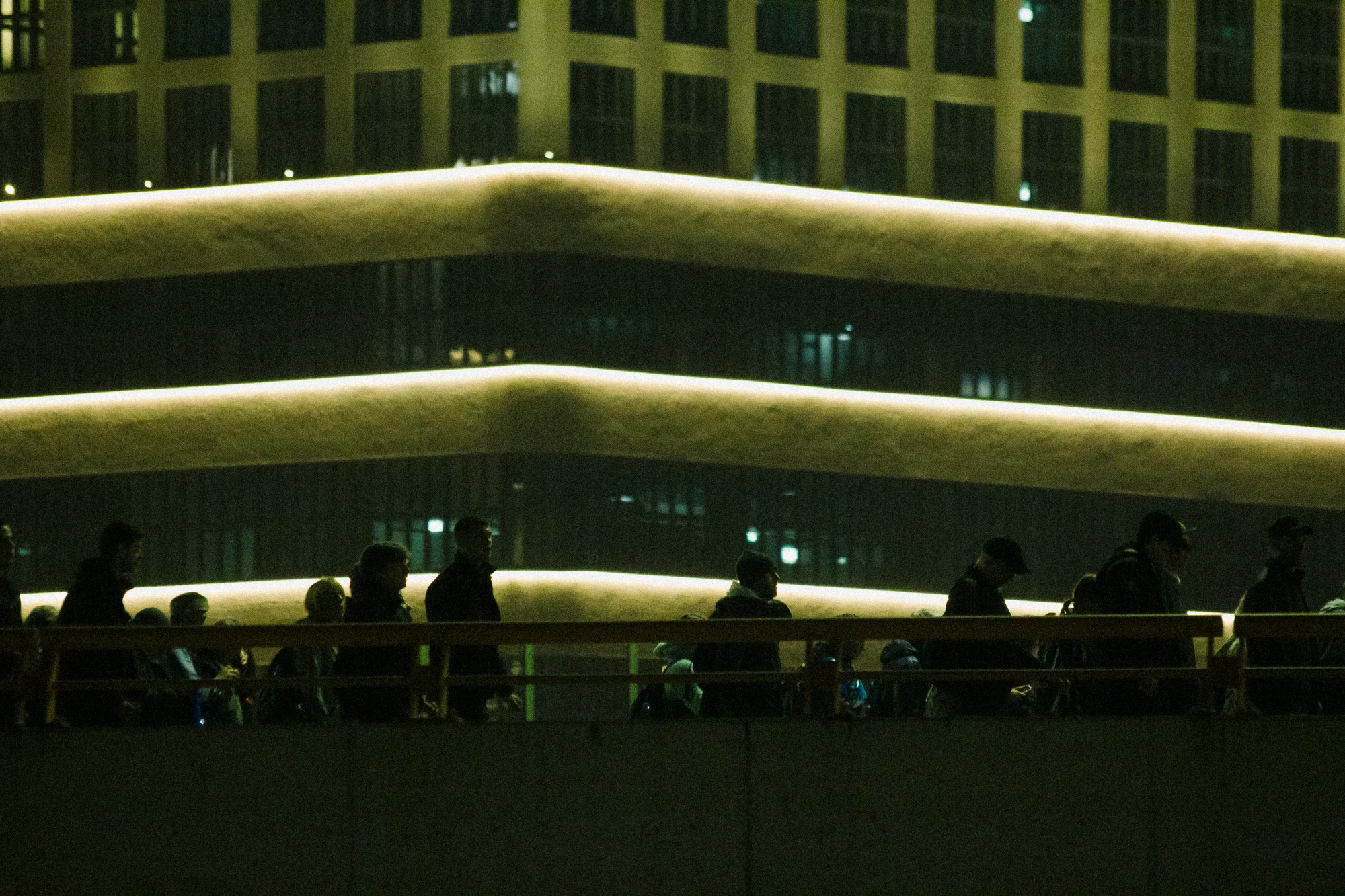 People are walking on a bridge at night in a city