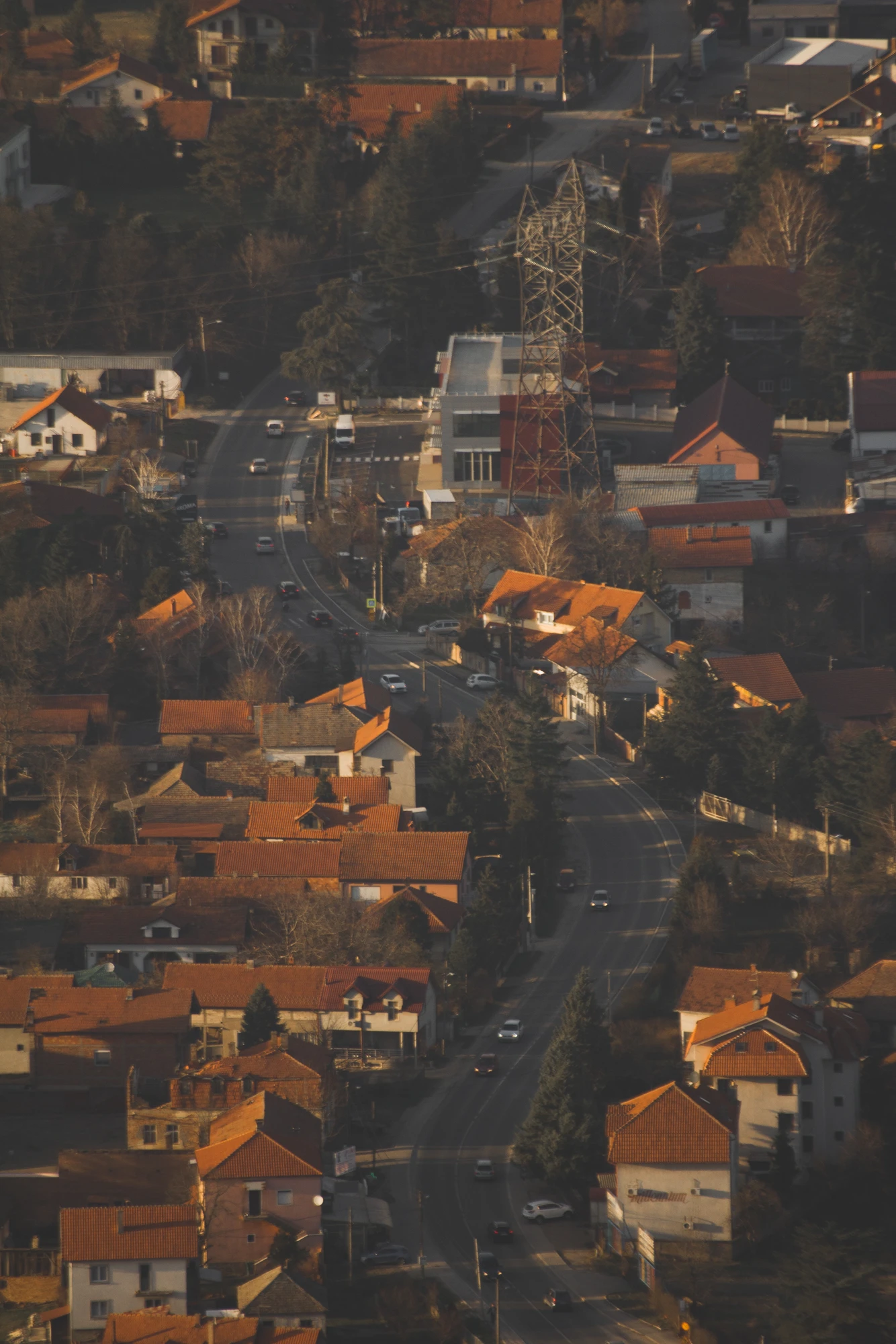A wavy street going through a city region with red tile roof houses and trees