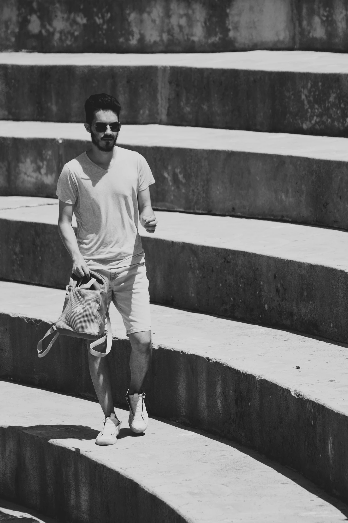 A person with sunglasses walking on amphitheatre stairs