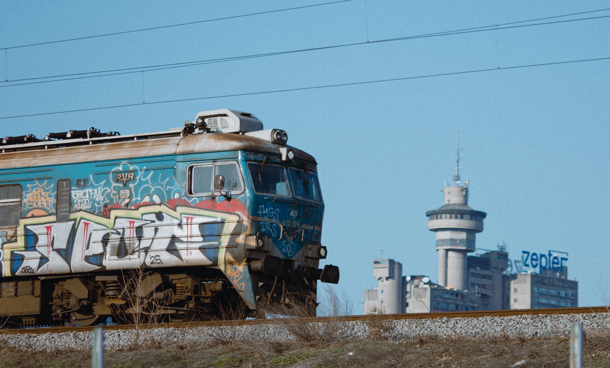 A train with graffiti on the tracks in front of the Western City Gate