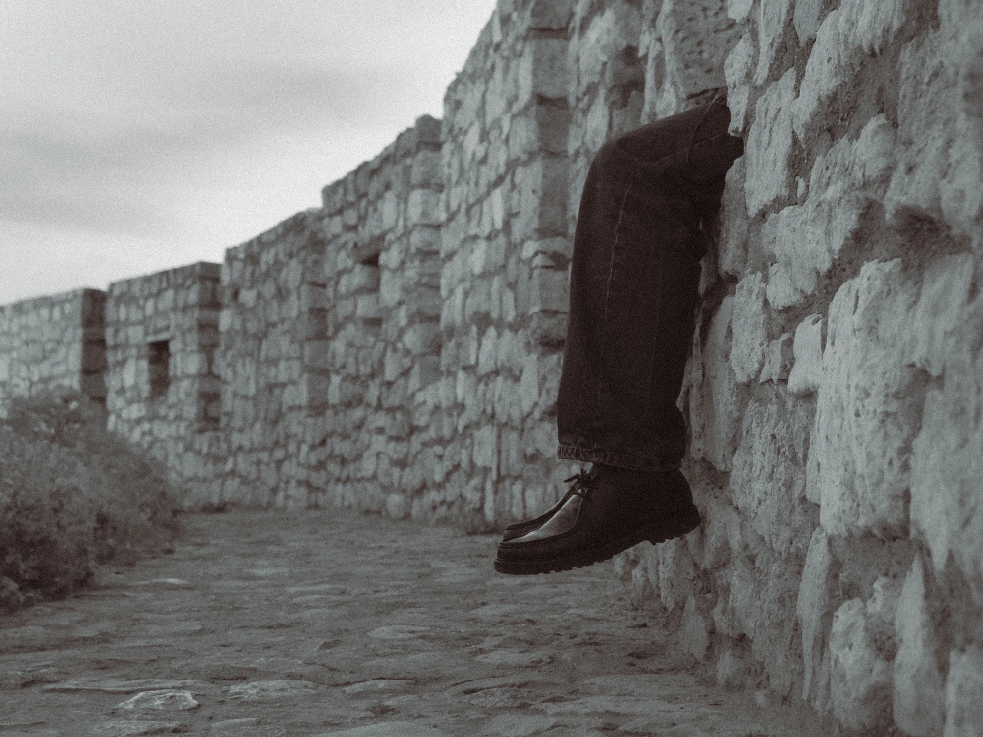 A pair of legs sticking out of the cobblestone fortress wall